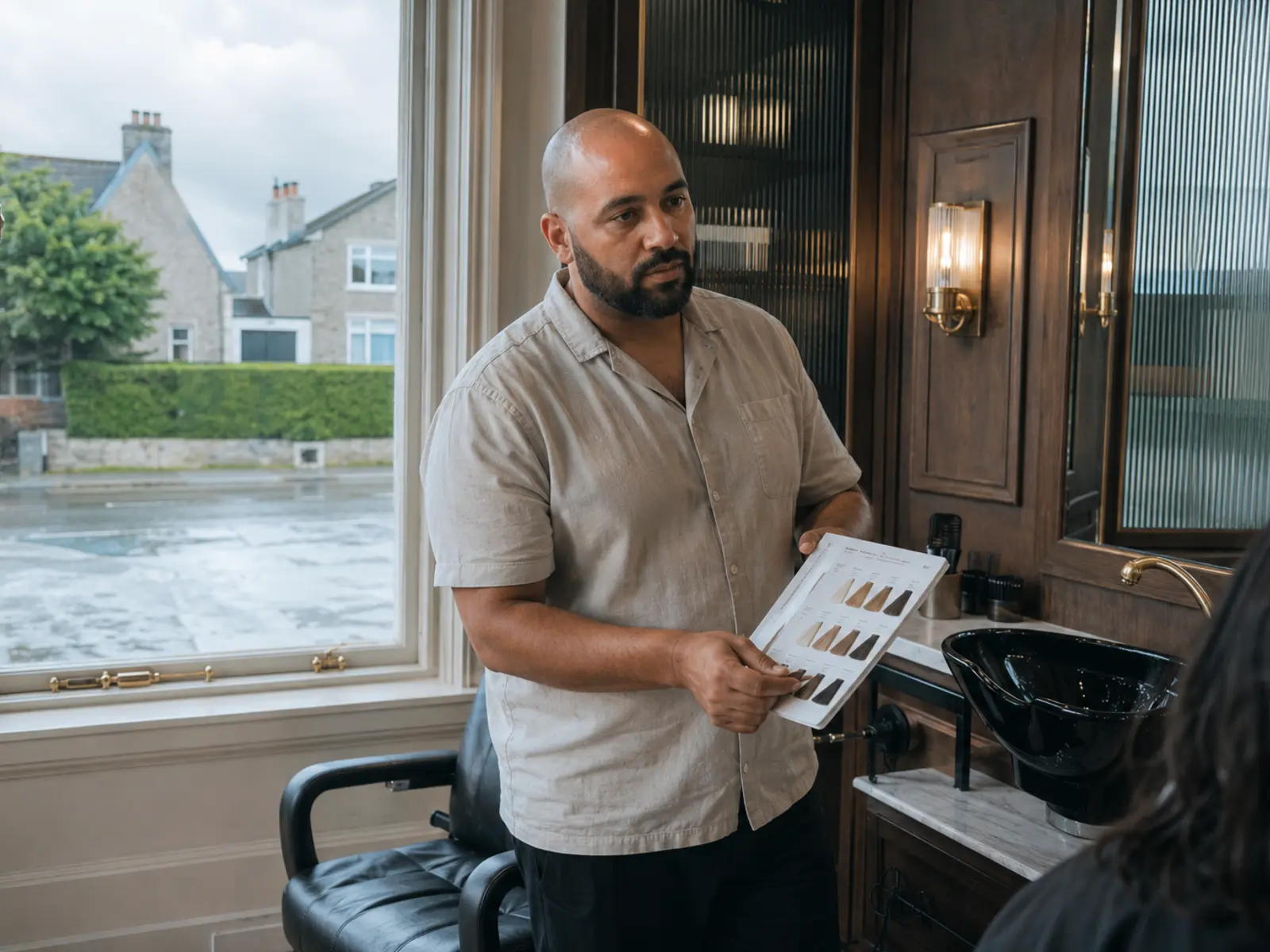 A stylist finishing a client blow-dry in a small salon