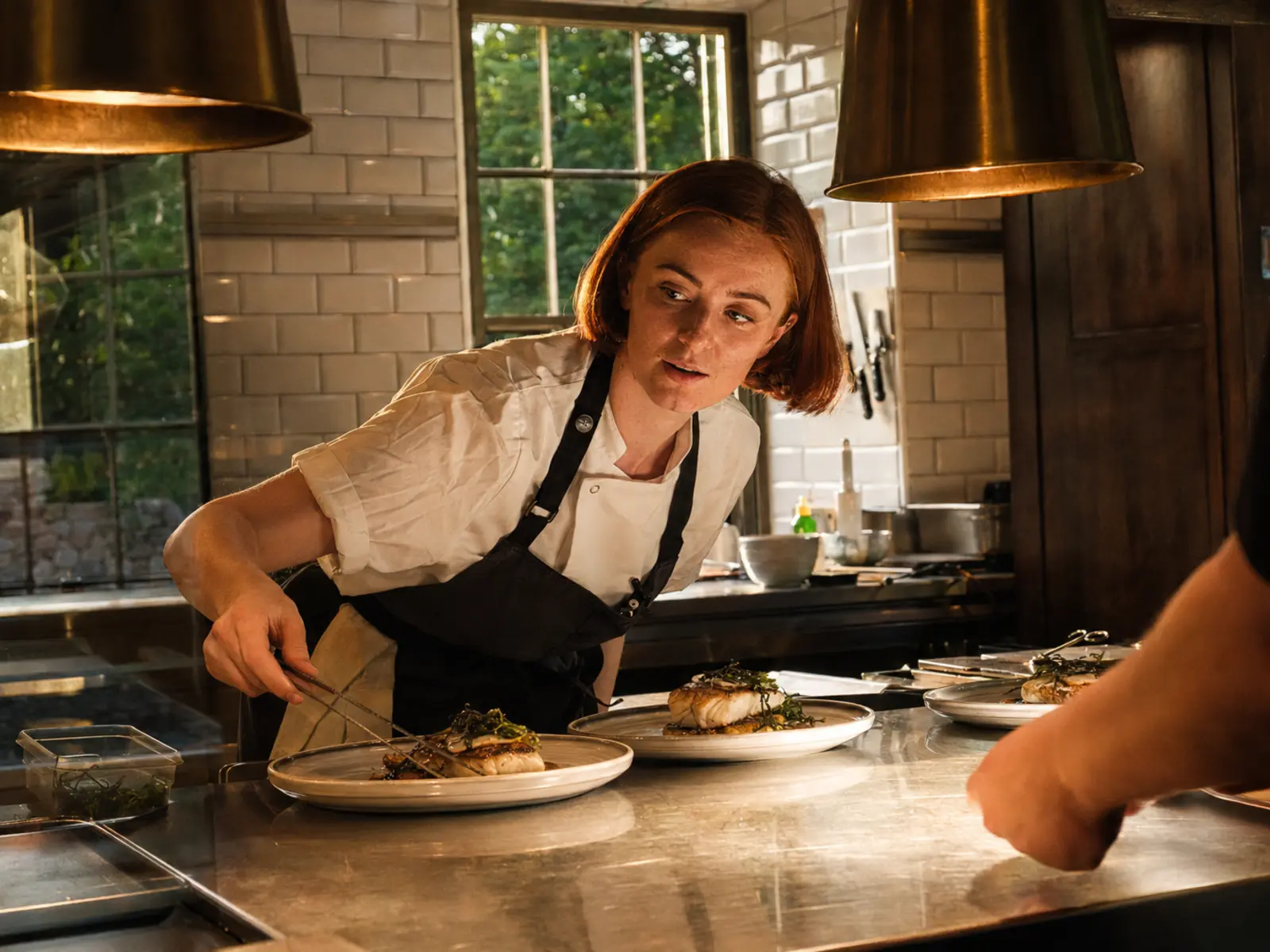 A chef plating seafood in a busy restaurant kitchen
