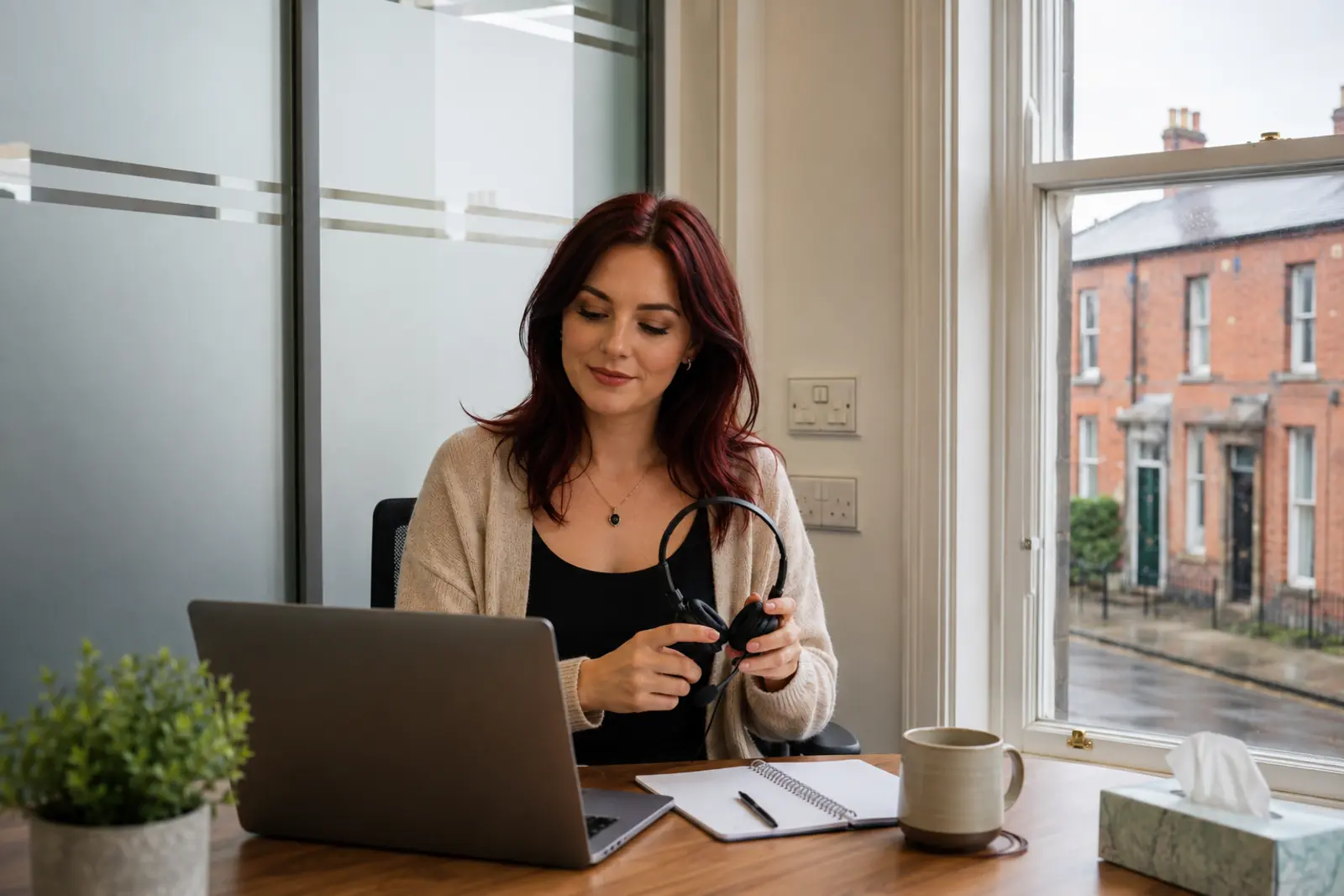 A counsellor at her desk with a laptop and headset ready for an online session