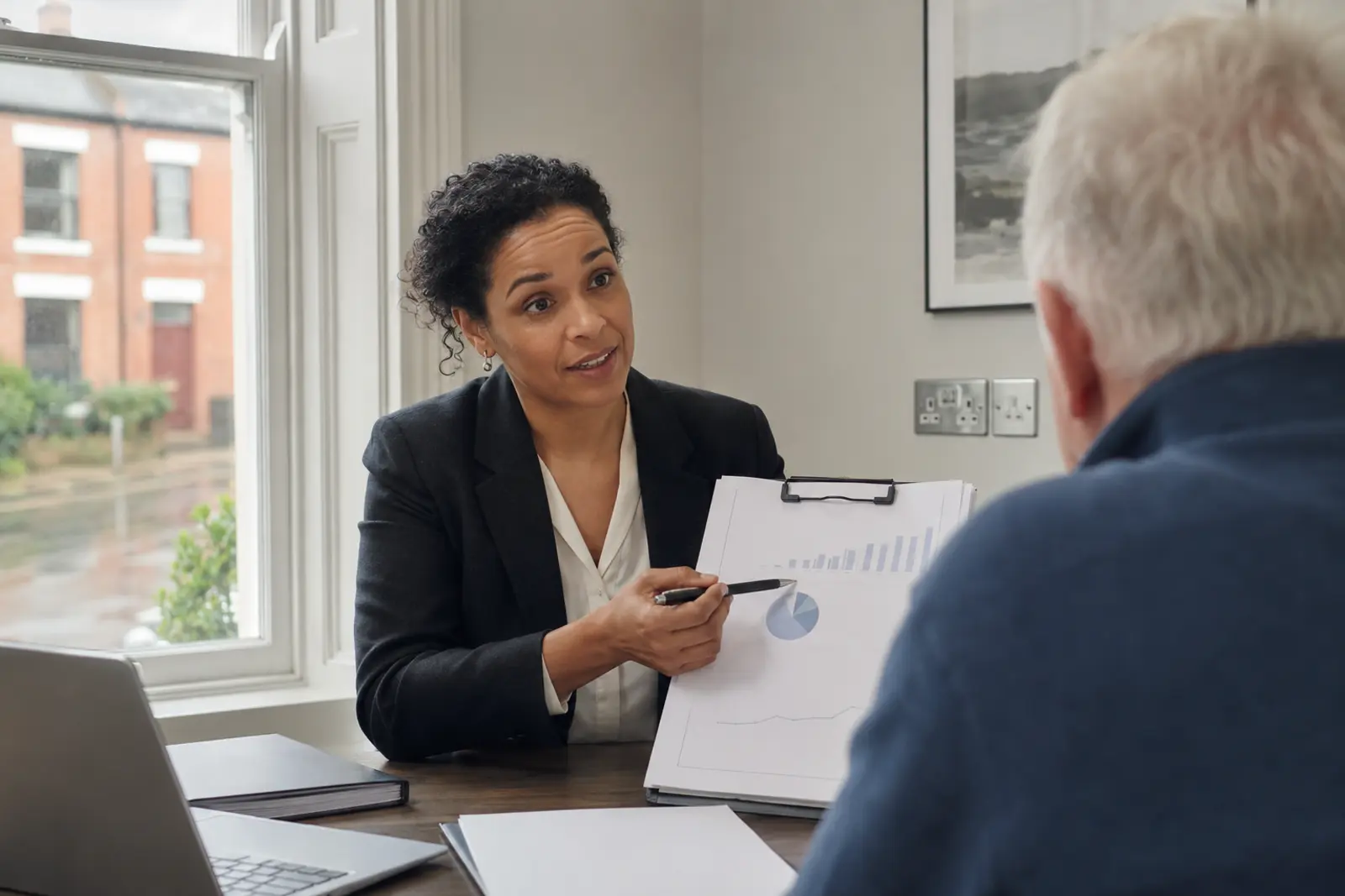A financial advisor talking a client through pension charts across a desk