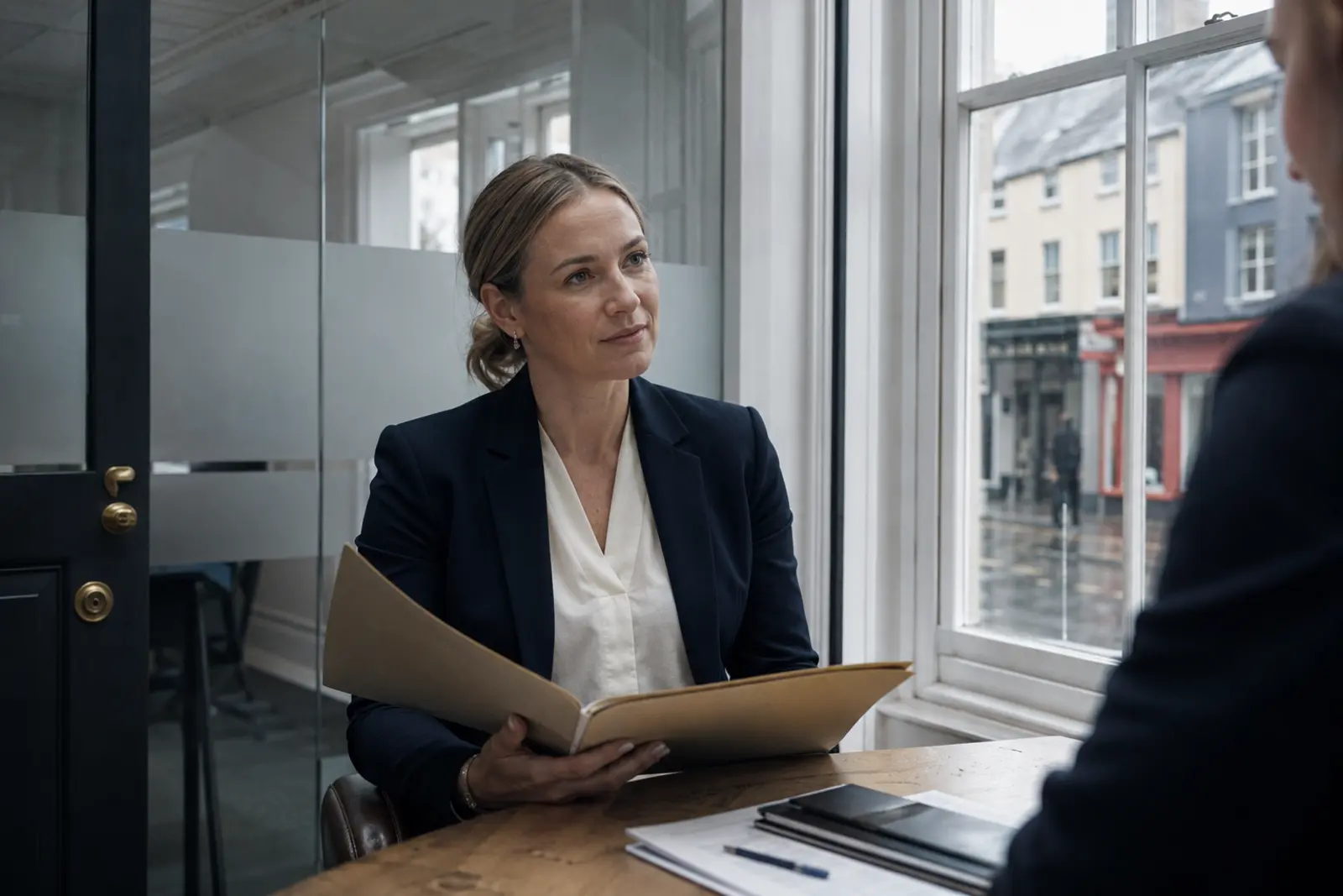A solicitor with an open file meeting a client across a desk