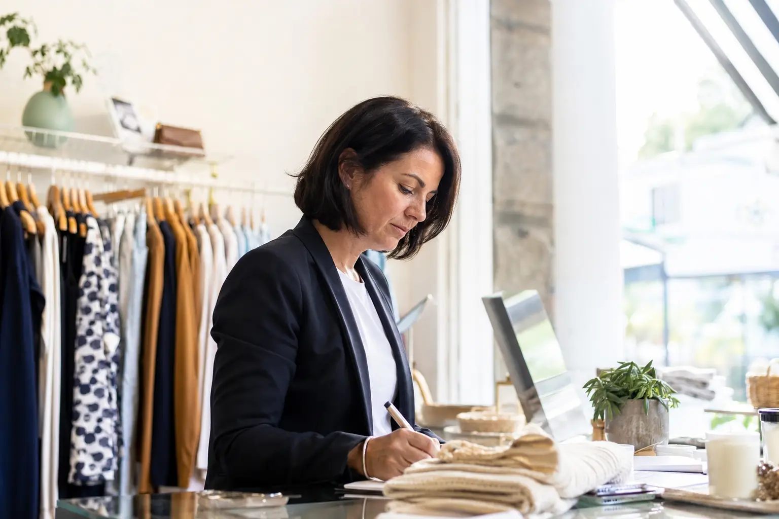 An Irish shop owner reviewing her business on a laptop at the counter